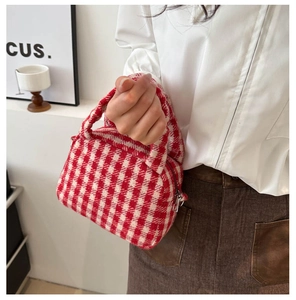 Dettaglio della borsa tote in maglia a scacchi rossi e bianchi con cerniera in metallo