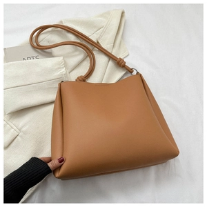 Detail view of brown faux leather tote bag with knot strap detail and smooth texture
