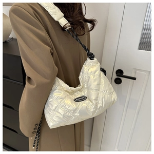Close-up of cream quilted puffer bag with glossy finish and rope strap detail