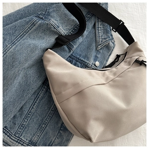 Detailed macro view of beige canvas crescent bag with black strap on denim jacket