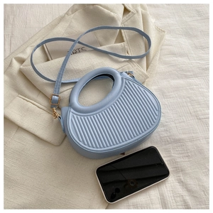 Detailaufnahme der hellblauen gestreiften Handtasche mit rundem Griff und Gold-Hardware