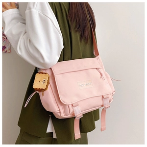 Détail du sac messager rose en nylon avec rabat et pendentif mignon en forme de biscuit