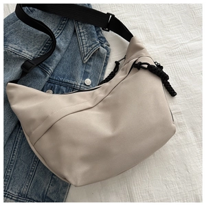 Detail view of beige canvas crescent bag featuring adjustable black nylon strap and woven puller