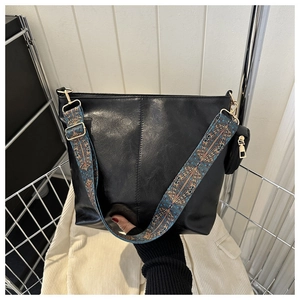 Detail of black leather tote bag with ethnic style wide strap and mini coin purse