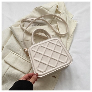 Detail view of cream white quilted crossbody bag with textured leather and gold buckle