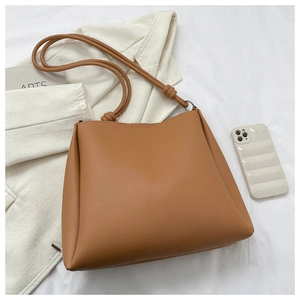 Detailed view of caramel PU leather bucket bag with a knotted shoulder strap and soft texture