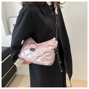 Pink quilted puffer bag with thick woven rope shoulder strap shown on a black coat