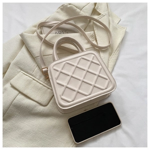 Detail of beige quilted faux leather handbag with gold hardware and top handle