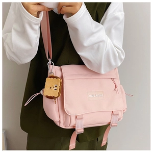 Détail du sac à bandoulière en nylon rose avec boucle et joli pendentif en forme de biscuit