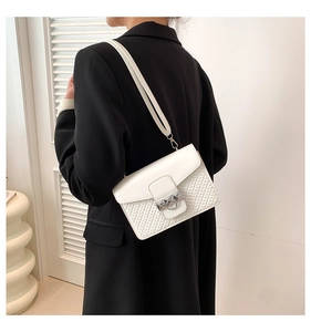 Detail of white shoulder bag with smooth flap and woven texture showing silver metal lock