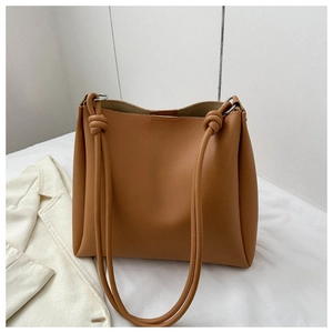 Detail of caramel brown tote bag featuring knotted shoulder strap and silver metal ring