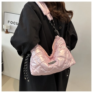 Pink quilted puffer bag with glossy finish and fashion logo shown on a model