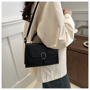 Detail of a black square leather handbag with gold magnetic buckle and adjustable strap
