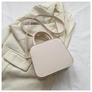 Top view of cream white rhombic square bag on a suit jacket with minimal texture detail