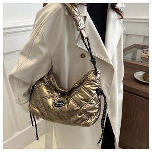 Quilted gold shoulder bag featuring a woven strap and fashion patch in a lifestyle setting
