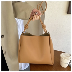 Close-up of knotted handle detail on a camel leather tote bag for professional women