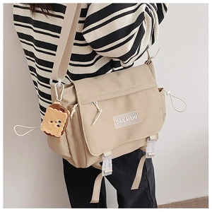 Détail du sac bandoulière en nylon beige avec cordon latéral et breloque en pain