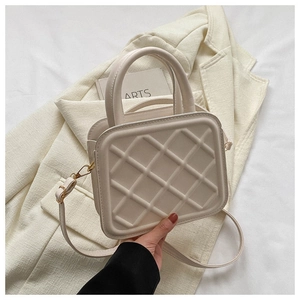 Detail of cream quilted crossbody bag with 3D diamond texture and golden hardware