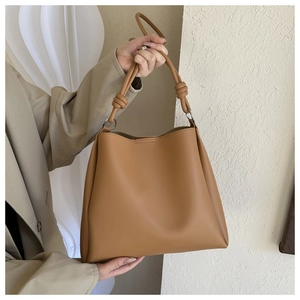 Detail of caramel brown tote bag showing the knotted strap and smooth leather texture