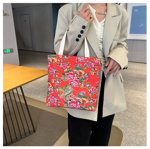 Detail of red floral canvas tote with traditional peony pattern on model in beige suit