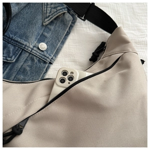 Detail of beige canvas crossbody bag front pocket with a smartphone inside for size reference