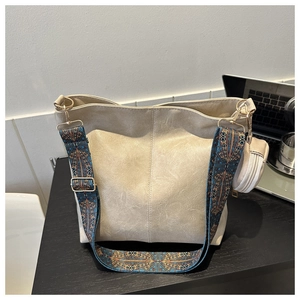 Detail of beige bucket bag with ethnic patterned wide strap and mini round coin purse