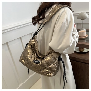 Close-up of quilted gold metallic padded bag with braided shoulder strap detail