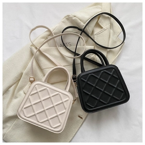 Detail of quilted leather crossbody bag in cream and black with gold hardware
