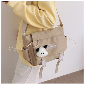 Détail du sac messager en nylon beige avec breloque chiot en peluche et bandoulière