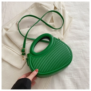 Detail der grünen Handtasche mit plissierten Streifen und integriertem Rundgriff