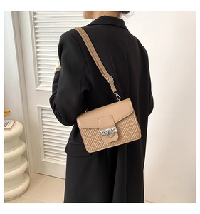 Detail showing the beige leather crossbody bag with weave texture and silver ring buckle