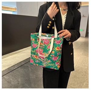 Detailed macro of green floral canvas tote bag with traditional peony and dragon patterns