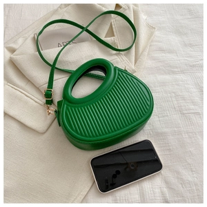 Detail der grünen Mini-Handtasche mit Faltentextur und Smartphone zum Größenvergleich