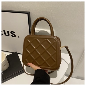 Detail view of brown quilted crossbody bag with golden hardware and leather strap