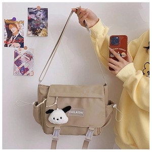 Détail du sac messager beige en nylon avec rabat, boucle et pendentif en peluche doux