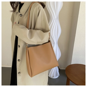 Minimalist light brown leather tote bag styled with a beige trench coat in a modern room