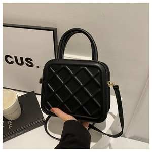 Close-up of black quilted crossbody bag with golden hardware and elegant handle