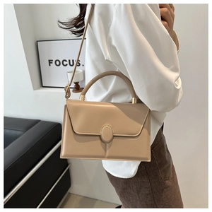 Model wearing a minimalist beige crossbody bag with gold metal buckle and thin shoulder strap