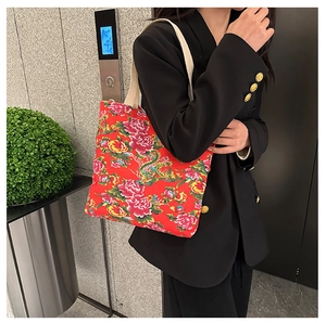 Close-up of red canvas tote bag with traditional floral print and off-white straps