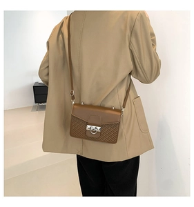 Detailed view of brown crossbody bag featuring woven texture and silver metal ring buckle