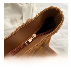 Détail de la fermeture éclair dorée et de la texture en peau de mouton du sac marron