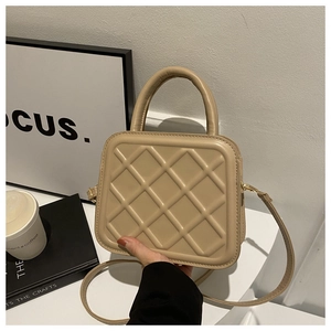 Close-up of beige quilted crossbody bag with top handle and adjustable shoulder strap