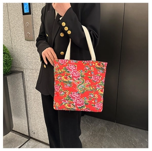 Detail of red floral canvas tote bag with traditional pattern worn by model
