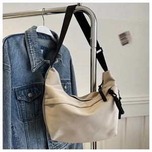 Detail of minimalist beige canvas crescent bag with black adjustable strap and knot zipper