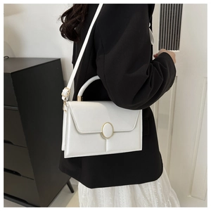 Detailed view of a white vintage square crossbody bag with gold buckle on a model