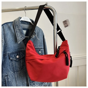 Detail view of large red canvas dumpling bag with black adjustable wide strap
