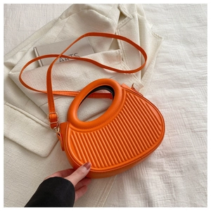 Detailansicht der orangefarbenen runden Handtasche mit vertikaler Streifenprägung und Griff