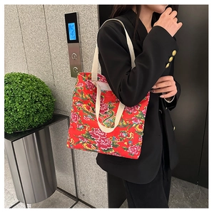 Detail of red floral canvas tote bag with traditional Chinese peony pattern on black suit
