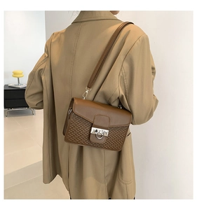 Detail of vintage brown crossbody bag featuring woven texture and silver buckle on a model