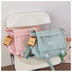 Détail de sacs bandoulière en nylon rose et vert avec boucles et breloques biscuits